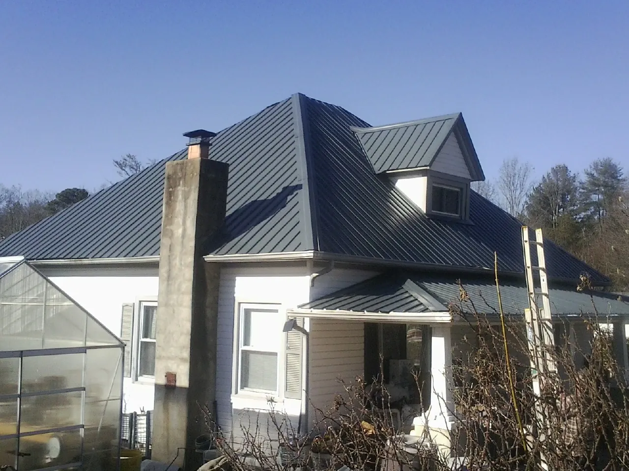 Dark blue standing seam metal roof on a white farmhouse with dormer — Slate & Tile Roof Repair by Roofing Brothers in Eure