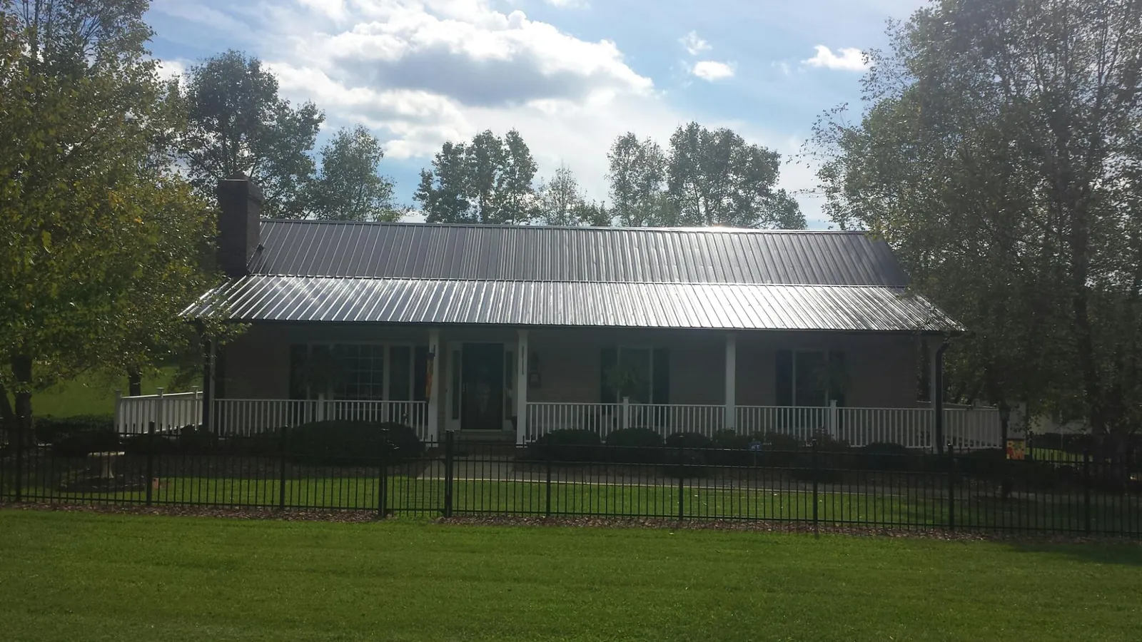 Gray metal roof on a brick ranch with a full width front porch — Gutter Guard Installation work by our crew in Eure