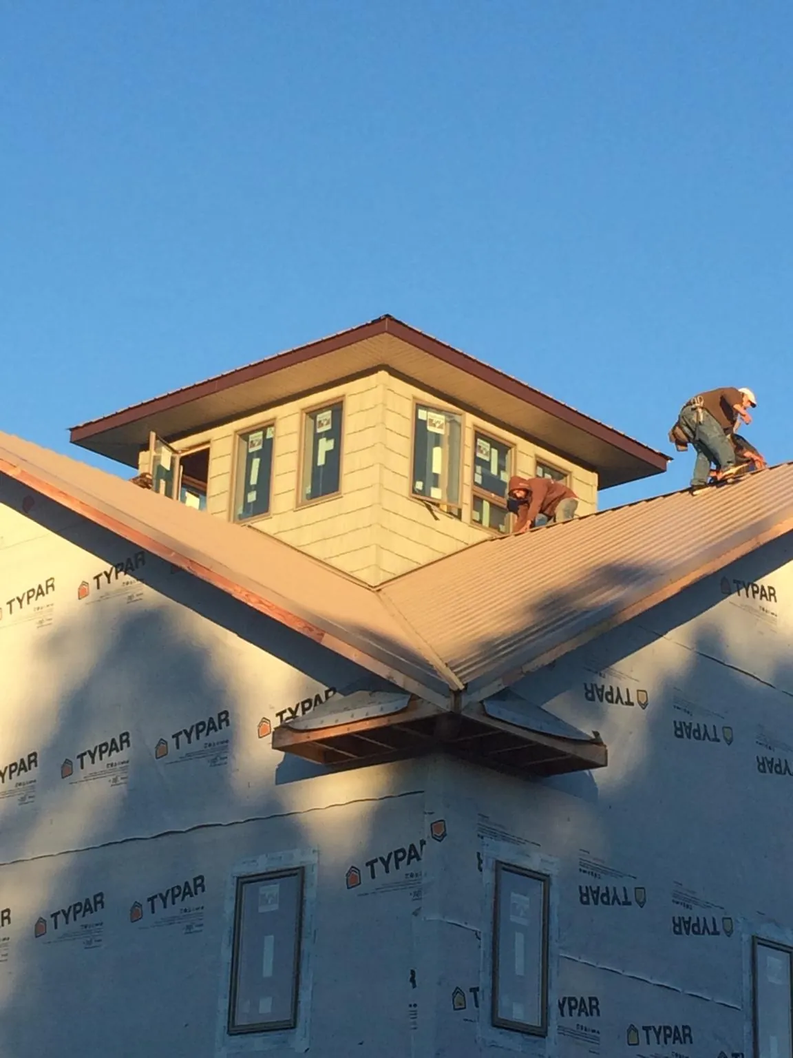 Roofers working around a rooftop cupola on a new metal roof at sunset — Roof Waterproofing in Eure by Roofing Brothers